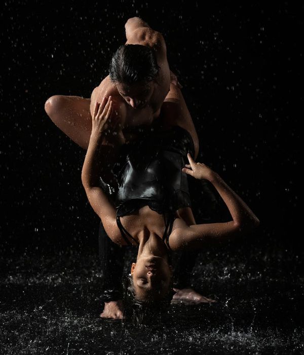 Woman performing a fluid cardio movement in a calm, dark studio.